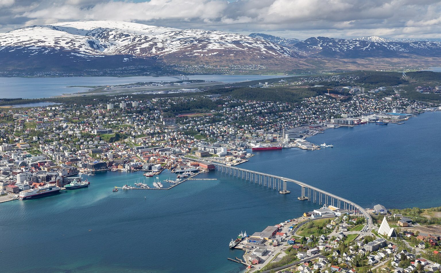 Tromsø harbour and the Tromsø Bridge seen from Fjellheisen, with the Arctic Cathedral and snow-capped mountains