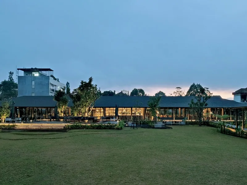 Wheels Coffee Roasters Juanda 256 in Dago, Bandung, at dusk: a wide lawn in front of the lit café pavilion