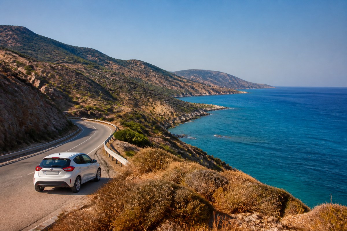 Hire car on a Cypriot coastal road with left-hand traffic flow, suggesting LHD and cross-border planning