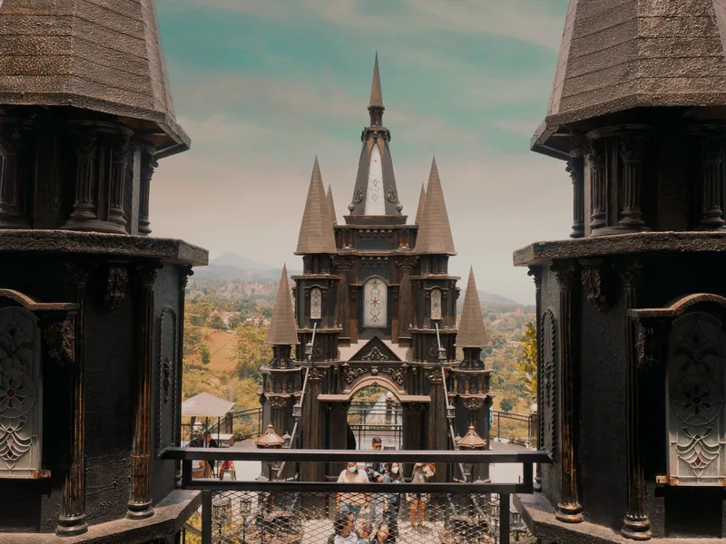 Dago Bakery Punclut’s castle-style building with dark spired towers, framed between two ornate turrets, with green hills behind